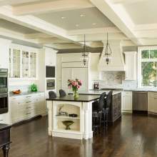 This kitchen is a comfortable and functional space, complete with white appliances, two dining tables, and a center island with a vase of flowers.