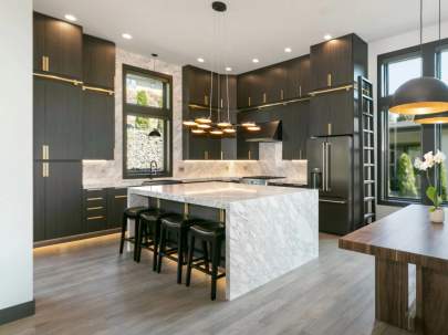 textured black cabinets with gold handles and a seemless granite island